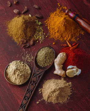 Various indian Spices arranged on a wooden surface