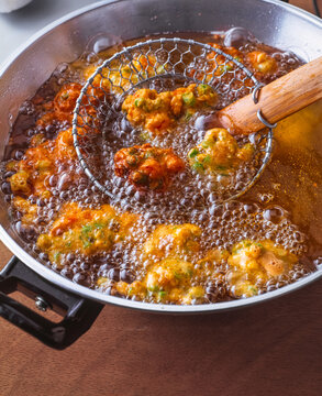 crispy Pakora ( Indian Vegetable fritters ) in hot oil in a wok 