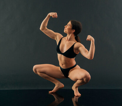 Woman in athletic pose wearing black sportswear against a dark background.