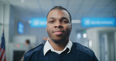 Airport Security Checkpoint: Portrait of African American Security Officer in Uniform Looking at...