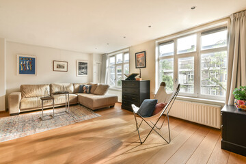 A spacious and cozy living room featuring large windows, modern furniture, and warm wooden floors that create a welcoming atmosphere.