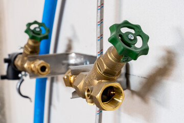 Dual brass water valves with green handles in plumbing system