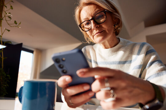 Blonde woman using her mobile phone at home