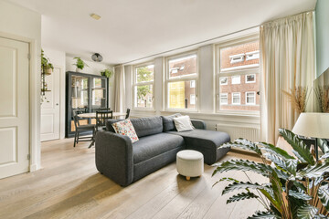 Cozy modern living room showcasing comfortable furniture, ample natural light through large windows, and a touch of greenery from indoor plants.