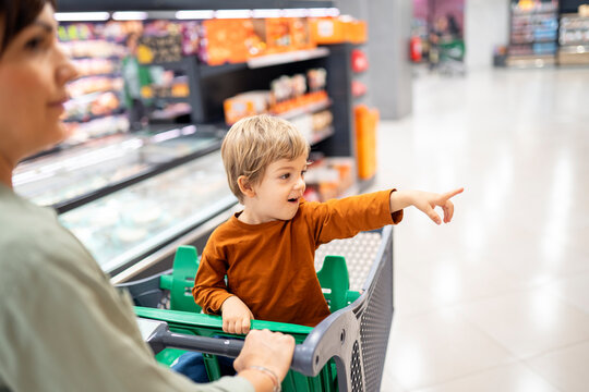 Boy pointing at something while sitting in shopping cart