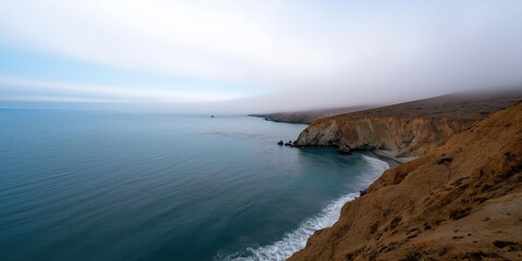 Obraz premium A foggy day with a beautiful ocean view. The water is calm and the sky is cloudy