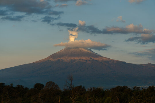 Popocatepetl volcano emitting smoke and ash at sunset