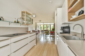 A sleek and contemporary kitchen featuring minimalist cabinetry, natural wood flooring, and an open layout that promotes light and space. Ideal for modern living.