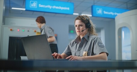 Airport Security Checkpoint: Female TSA Officer Wearing Headset Works on Laptop. Transportation...