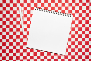 Blank sketchbook and pen on red and white checkered background