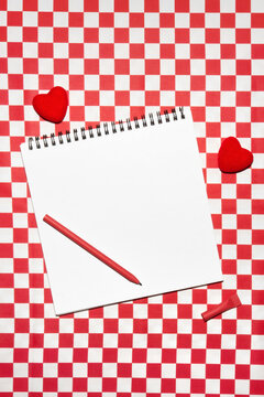 Blank sketchbook, pen and hearts on red and white checkered background