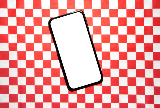 Smartphone with blank white screen on red and white checkered backdrop