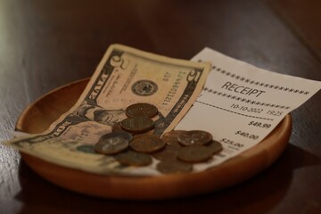 Tip and receipt on wooden table, closeup
