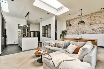 Elegantly designed living room showcasing a modern aesthetic with natural light filtering through skylights, paired with stylish furniture and decor.