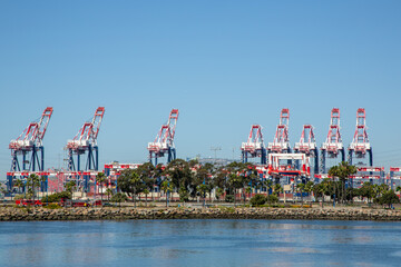 Shipping cranes and port infrastructure. Fire trucks in seaport with cranes. Large industrial port cranes stand tall at a busy shipping dock. Massive cranes dominate harbor skyline under a clear sky.