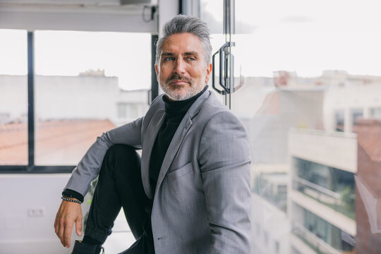 Confident businessman in gray suit looking out office window