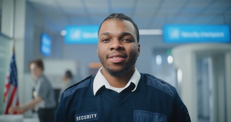 Airport Security Checkpoint: Portrait of African American TSA Worker Smiling and Looking at Camera....