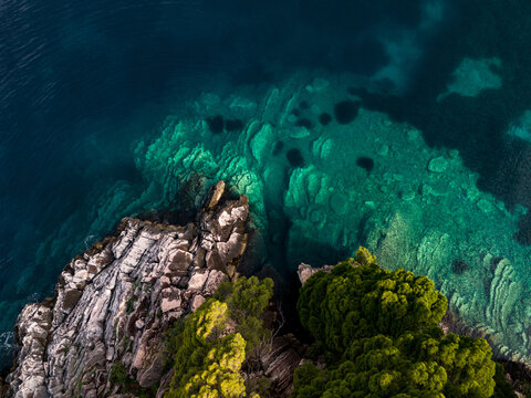 Top down drone shot of rocky sea bottom a turquoise sea water