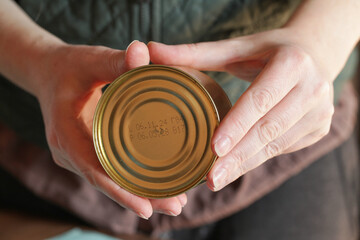 Canned Fish with expiration date. Woman Reads labels and looks at the expiration date