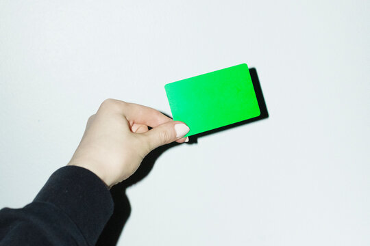 Hand holding green credit bank money payment card with hard flash
