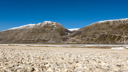 View from below of a valley with snow-capped mountains in the background.