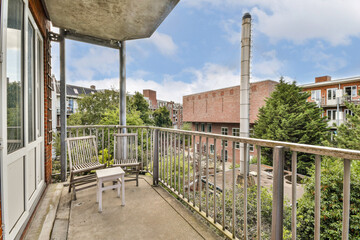A spacious balcony offering a view of the urban landscape, featuring greenery and buildings, perfect for relaxation and enjoying outdoor moments.