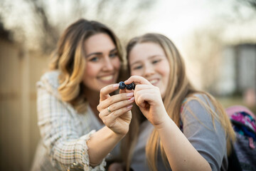 Mother and daughter joyfully sharing blueberries, showcasing friendship and connection in a delightful outdoor setting.
