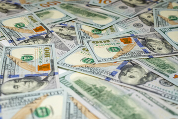 Stacks of hundred-dollar bills are spread out on a surface emphasizing the details of the new currency design side view in close up