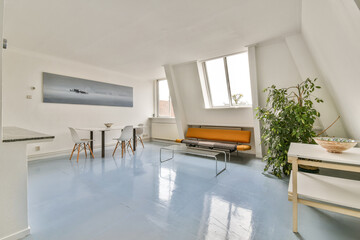 A spacious, well-lit modern interior featuring minimalist furniture, a bright blue floor, and greenery, creating a refreshing atmosphere for relaxation.