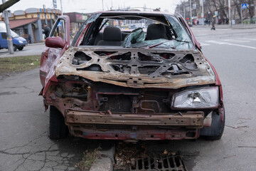 A dilapidated and rusting car is left abandoned on the roadside, vividly showcasing the profound effects of time and neglect in an urban environment, capturing both decay and history