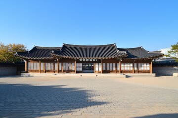 Fototapeta premium Korean traditional wooden house in courtyard, sunny day, park in background
