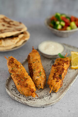 Chicken Kofta Kebab on wooden skewers with pita, garlic sauce Toum, parsley, lemon, cucumber and tomato. Shish kafta tavuk. Traditional Middle East food. Lebanese, Turkish cuisine. Food photography.