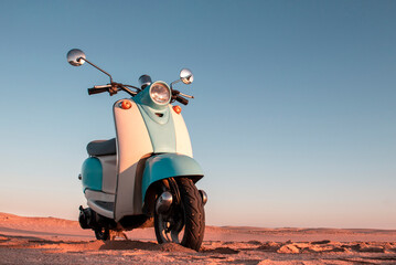 Retro blue scooter at sunset in the golden sand of the Namib Desert
