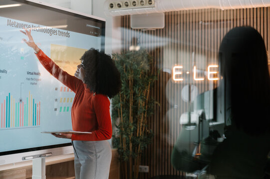 Woman analyzing metaverse trends on interactive whiteboard in office