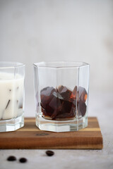 Two cups of Japanese coffee jelly with coconut milk and coffee beans in the background. Dessert made from Black coffee jelly cubes. Vegan food concept. Healthy dessert