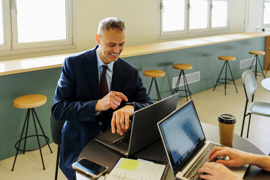 Formal businessman using smartwatch in modern office - Powered by Adobe