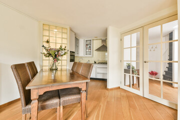 Stylish dining area featuring a wooden table, comfortable chairs, and a bouquet of flowers, complemented by elegant glass doors and natural light.