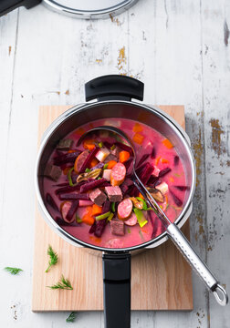Colorful beet soup with vegetables and sausage in a pot ready to serve