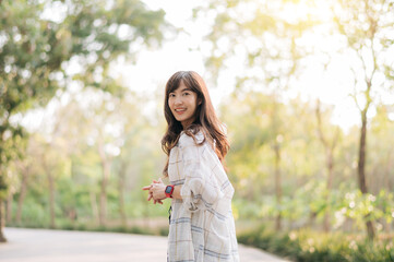 Asian woman enjoying summer outdoors, breathing fresh air with joyful smile, surrounded by lush...