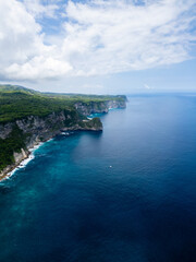 Stunning cliffside view at Manta Point, Nusa Penida &ndash; turquoise waters crashing against rugged limestone cliffs under a bright blue sky
