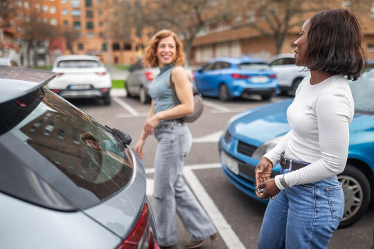 multiracial friends putting shopping bags in the trunk of a car