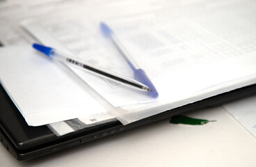 A pen and a blue pen are on top of a piece of paper
