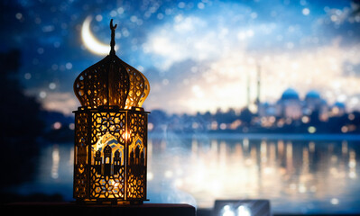 ornamental Arabic lantern with burning candle glowing at night and mosque in background. Festive...