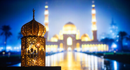 ornamental Arabic lantern with burning candle glowing at night and mosque in background. Festive...