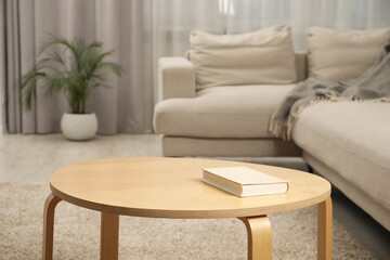 Book on wooden coffee table near sofa in living room