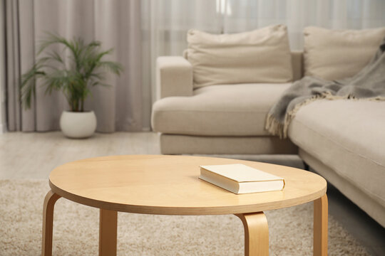 Book on wooden coffee table near sofa in living room