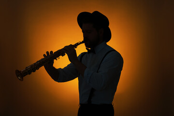 Professional musician playing soprano saxophone on color background, backlit