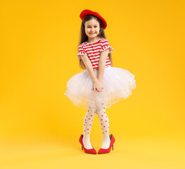 Stylish little girl wearing oversized high heeled shoes on orange background, space for text