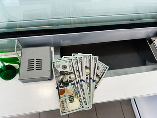Stack of hundred dollar bills on counter at a financial transaction window