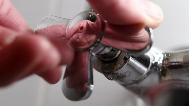 An old metal hot water faucet is covered with rust and limescale, dripping water from underneath, emphasizing the leakage problem.
